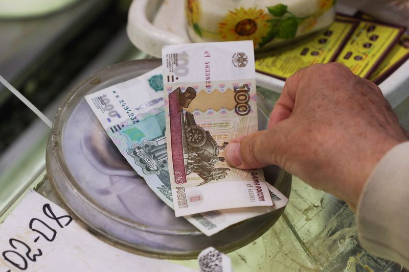 &copy; Reuters. FILE PHOTO: A customer pays with Russian rouble banknotes at a market in Saint Petersburg, Russia July 9, 2023.  REUTERS/Anton Vaganov/File Photo