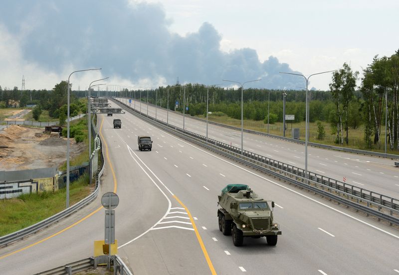 &copy; Reuters. FOTO DE ARCHIVO: Una columna militar del grupo mercenario privado Wagner conduce a lo largo de la autopista M-4, que une la capital Moscú con las ciudades del sur de Rusia, con el humo de un tanque de combustible en llamas en un depósito de petróleo vi