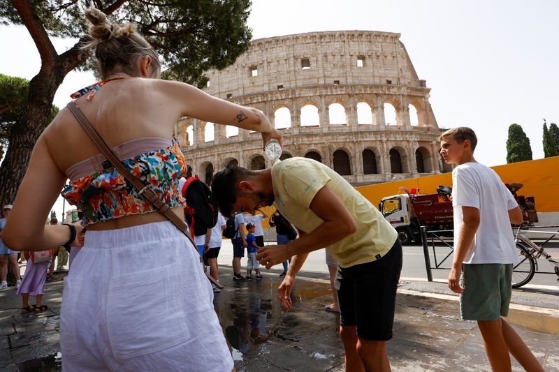 &copy; Reuters. A woman pours water on a man near the Colosseum, during a heatwave across Italy, as temperatures are expected to rise further in the coming days, in Rome, Italy July 18, 2023. REUTERS/Remo Casilli