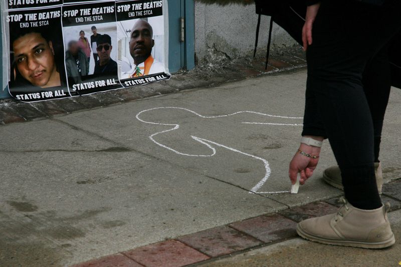 &copy; Reuters. FILE PHOTO: An activist draws a chalk outline of a body near pictures of victims who died while crossing the border between Canada and the United States, during a demonstration for Refugee Rights Day in front of Public Safety Minister Marco Mendicino's co