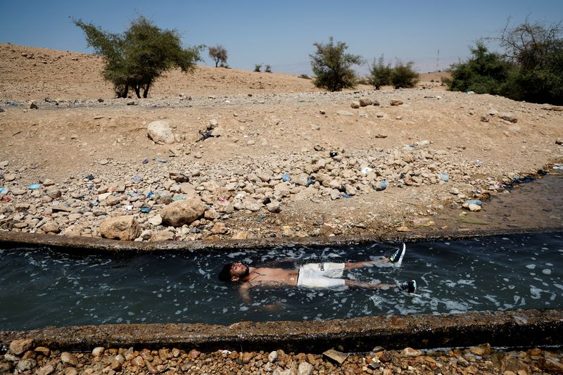 © Reuters. A Palestinian man cools off during a heatwave, in al-Oja Springs near Jericho in the Israeli-occupied West Bank, July 18, 2023. REUTERS/Ammar Awad