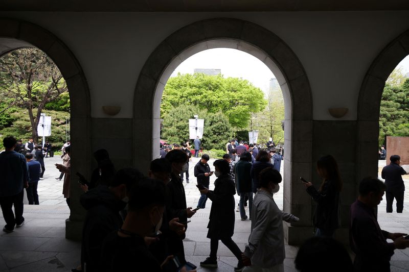 &copy; Reuters. FILE PHOTO: Office workers look at their mobile phones to check the local online banking app Toss as they gather at Seoul Museum of Art during a lunch break in Seoul, South Korea, April 13, 2023.  REUTERS/Kim Hong-Ji/File Photo