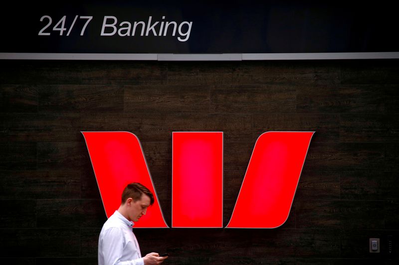 &copy; Reuters. FILE PHOTO: A pedestrian looks at his phone as he walks past a logo for Australia's Westpac Banking Corp located outside a branch in central Sydney, Australia, November 5, 2018.   REUTERS/David Gray/