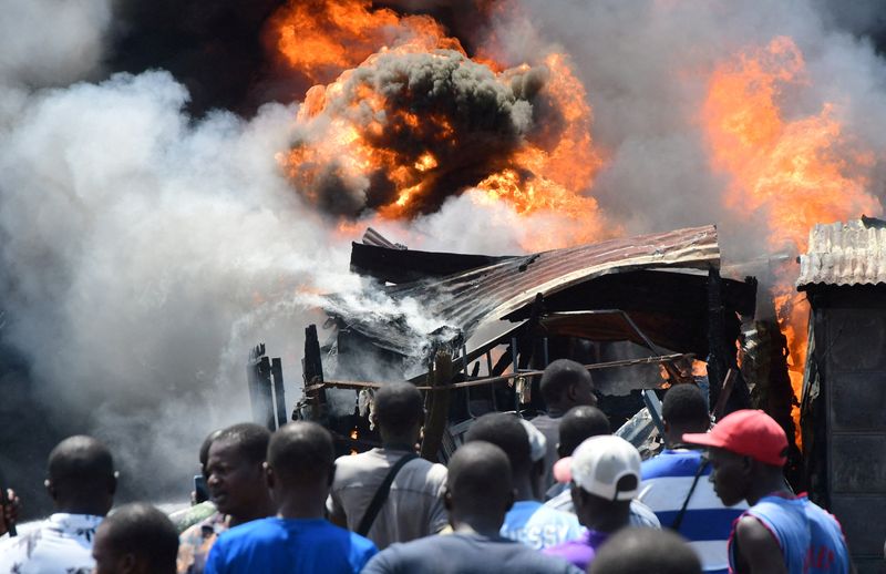 © Reuters. People gather near burning business premises after supporters of Kenya's opposition leader Raila Odinga of the Azimio La Umoja (Declaration of Unity) One Kenya Alliance, clashed with riot police officers as they participated in an anti-government protest against the imposition of tax hikes by the government, in Kisumu county, Kenya July 19, 2023. REUTERS/James Keyi