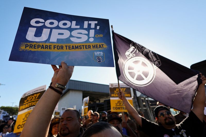 © Reuters. People hold placards during a rally held by teamsters employed by UPS in downtown L.A., as an August 1st strike deadline against the company nears in Los Angeles, California, U.S. July 19, 2023. REUTERS/Mike Blake