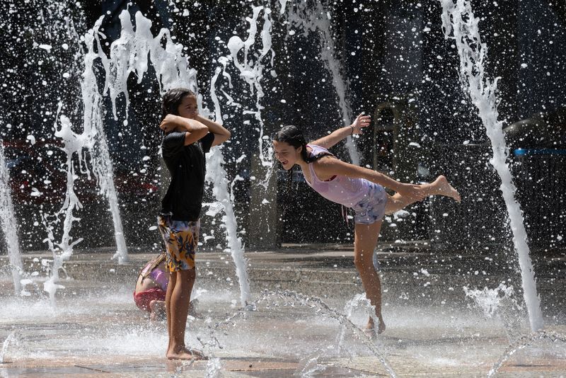 &copy; Reuters. Sisters Olivia, 10, and Evelyn Black, 12, play in Gateway Fountains at Discovery Green park to escape the hot weather in Houston, Texas, U.S., July 18, 2023. REUTERS/Adrees Latif