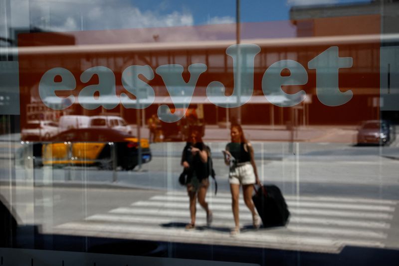 &copy; Reuters. FILE PHOTO: Passengers reflected on a glass with an Easyjet logo on it walk at Josep Tarradellas Barcelona-El Prat Airport during an Easyjet's cabin crew strike, in Barcelona, Spain, July 1, 2022. REUTERS/Albert Gea/File Photo