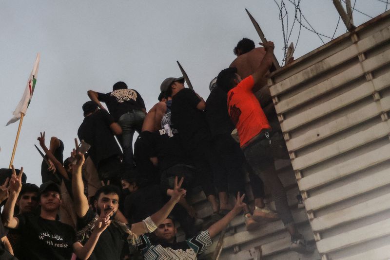 &copy; Reuters. متظاهرون يتسلقون سور السفارة في أثناء تجمعهم أمام السفارة السويدية ببغداد بعد ساعات من اقتحام السفارة وإضرام النار بها في بغداد يوم الخميس.