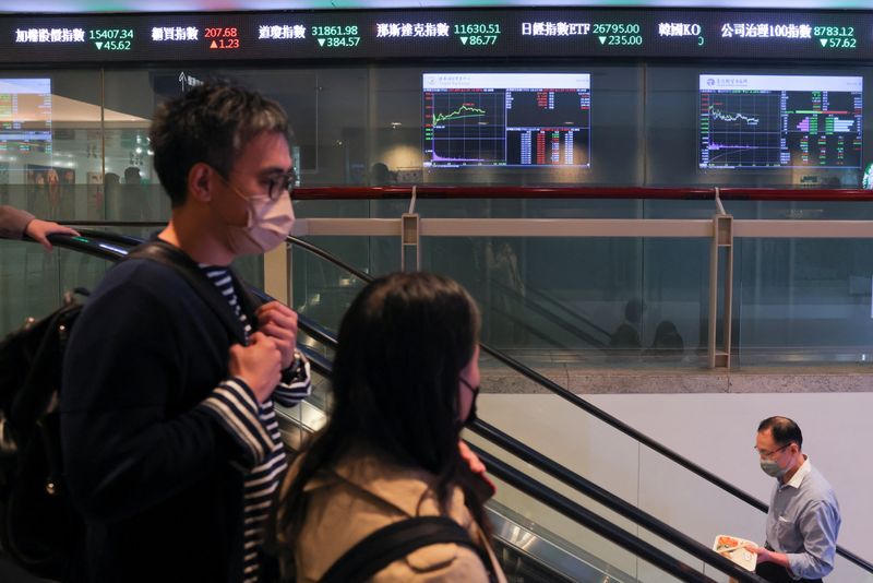 &copy; Reuters. FILE PHOTO: People wearing face masks pass in front of screens showing trading data, while using the escalators outside Taiwan Stock Exchange, in Taipei, Taiwan March 20, 2023. REUTERS/Annabelle Chih