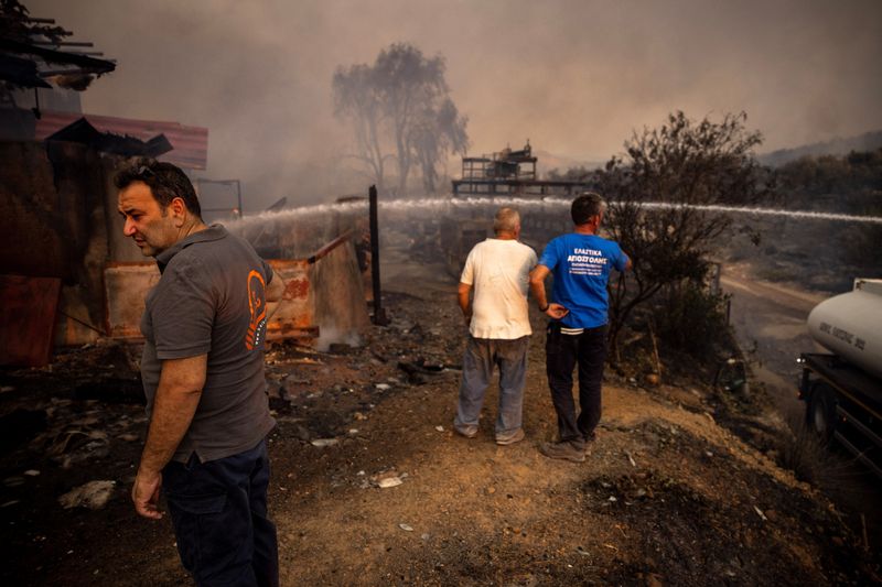 &copy; Reuters. أفراد من فرق إطفاء محلية يحاولون إخماد حريق في ساحة في ماندرا باليونان في 18 يوليو تموز 2023 في ظل استمرار لحرئق الغابات. تصوير ألكيس كونستانين