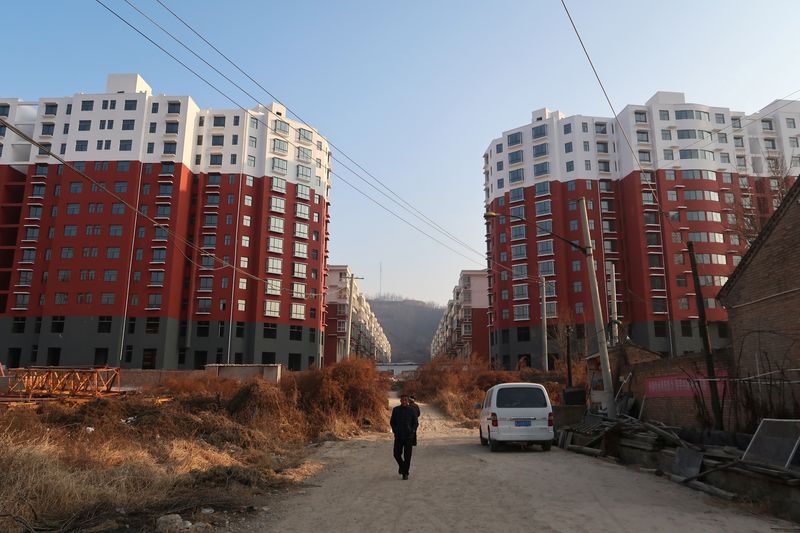 © Reuters. FILE PHOTO: A man walks near a shantytown to be redeveloped, in front of apartment buildings, in Fu county in the south of Yanan, Shaanxi province, China January 2, 2019. REUTERS/Yawen Chen/File Photo