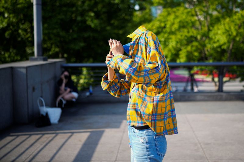 © Reuters. A person uses clothing to protect themselves from the sun, as they walk on the Bund on a hot day, in Shanghai, China May 15, 2023. REUTERS/Aly Song/File Photo