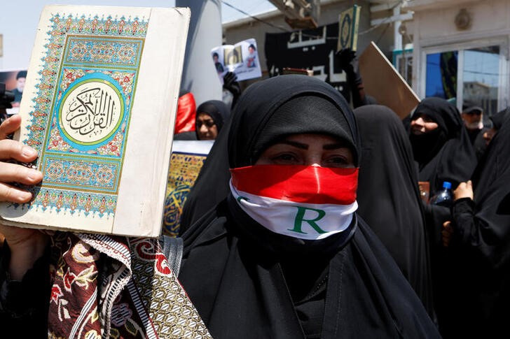&copy; Reuters. Una mujer muestra un Corán durante una protesta de fieles al clérigo chií Muqtada al-Sadr tras el asalto y quema de la embajada de Suecia en Bagdad, Irak. 21 julio 2023. REUTERS/Alaa Al-Marjani