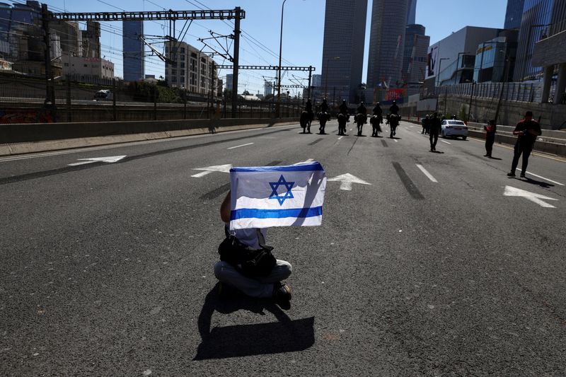 &copy; Reuters. FILE PHOTO: A protester sits on the ground as mounted police officers patrol the street, as Israelis demonstrate during "Day of Resistance", as Israeli Prime Minister Benjamin Netanyahu's nationalist coalition government presses on with its contentious ju
