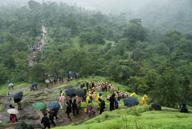 &copy; Reuters. أفراد القوة الوطنية للاستجابة للكوارث ومتطوعون آخرون يتسلقون جبلًا للوصول إلى موقع الانهيار الأرضي في قرية بولاية مهاراشترا بالهند يوم 20 ي
