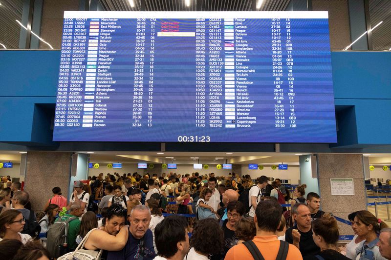 © Reuters. Tourists line up at check-in counters as they wait for departing planes at the airport, after being evacuated following a wildfire on the island of Rhodes, Greece, July 24, 2023. REUTERS/Nicolas Economou