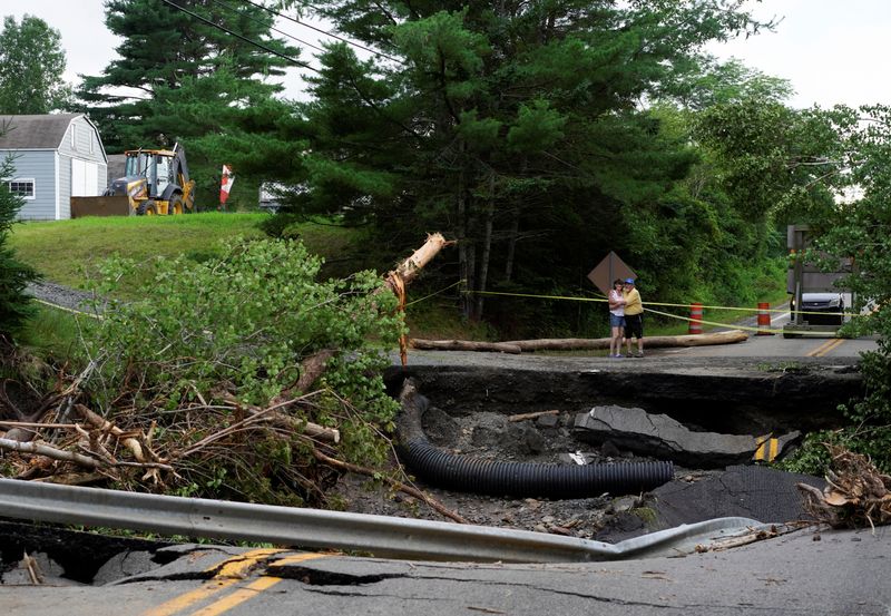 © Reuters. People embrace as they stand near damage to a road, after the heaviest rain to hit the Atlantic Canadian province of Nova Scotia in more than 50 years triggered floods, in Ellershouse, West Hants Regional Municipality, Nova Scotia, Canada July 23, 2023. REUTERS/John Morris
