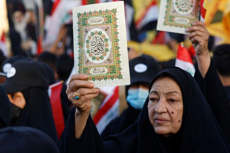 © Reuters. سيدة عراقية تحمل جزءا من القرآن خلال مظاهرة في بغداد في 22 يوليو تموز 2023 للاحتجاج على حرق نسخة من المصحف والعلم العراقي في العاصمة السويدية ستوكهولم . تصوير : خالد الموصلي - رويترز . 