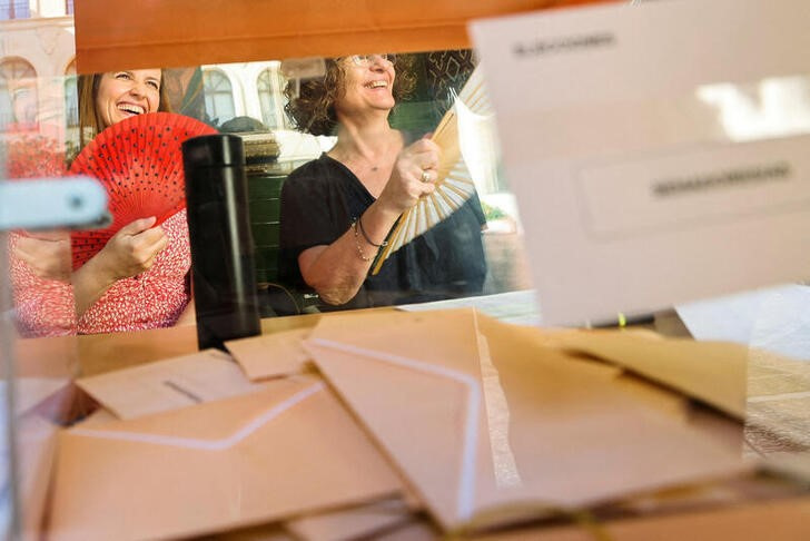 &copy; Reuters. FOTO DE ARCHIVO. Encargadas electorales utilizan abanicos mientras posan para una foto durante las elecciones generales anticipadas en Madrid, España. 23 de julio de 2023. REUTERS/Nacho Doce