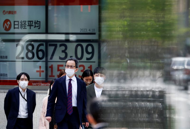 &copy; Reuters. FILE PHOTO: Passersby walk past an electric board displaying Japan's Nikkei share average outside a brokerage in Tokyo, Japan April 18, 2023.  REUTERS/Issei Kato