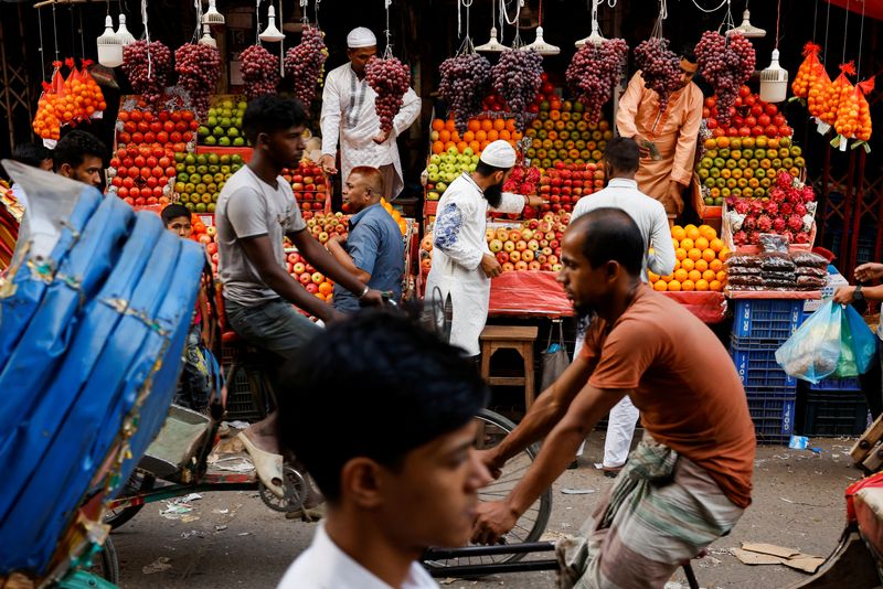 © Reuters. FILE PHOTO-Commuters pass by a fruit shop in Dhaka, Bangladesh, November 11, 2022. REUTERS/Mohammad Ponir Hossain/File Photo