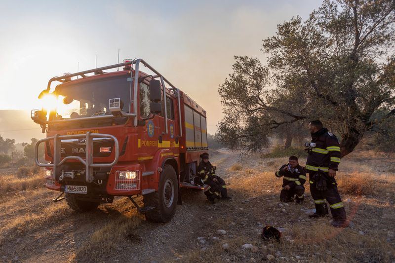 &copy; Reuters. Des pompiers roumains se reposent alors qu'un incendie de forêt brûle près du village de Masari, sur l'île de Rhodes, en Grèce. /Photo prise le 24 juillet 2023/REUTERS/Nicolas Economou