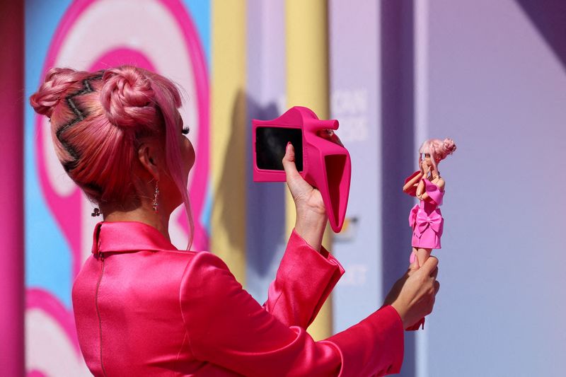 © Reuters. FILE PHOTO: A fan takes a photo of a Barbie doll at the world premiere of the film 