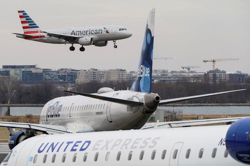 © Reuters. FILE PHOTO: An American Airlines aircraft flies past JetBlue and United Express aircraft as it lands at Reagan National Airport in Arlington, Virginia, U.S., January 24, 2022.   REUTERS/Joshua Roberts/File Photo