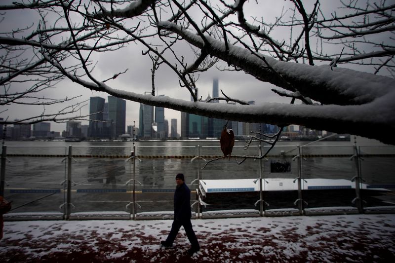 &copy; Reuters. FILE PHOTO: A man walks in front of Shanghai's financial district at the Bund promenade as snow falls in Shanghai, China January 26, 2018. REUTERS/Aly Song/File Photo