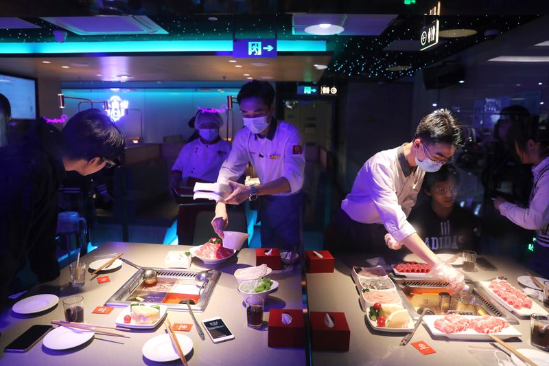 &copy; Reuters. FILE PHOTO: Waiters serve customers at a Haidilao hotpot restaurant in Beijing, China October 11, 2021. Picture taken October 11, 2021. REUTERS/Tingshu Wang/File Photo