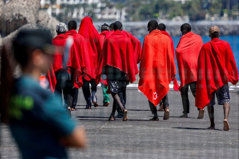 &copy; Reuters. Des migrants se dirigent vers une tente de la Croix-Rouge après avoir débarqué d'un navire des garde-côtes espagnols, dans le port d'Arguineguin, sur l'île de Grande Canarie, en Espagne. /Photo prise le 28 juillet 2023/REUTERS/Borja Suarez