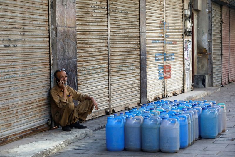 © Reuters. A shopkeeper uses mobile phone as he sits outside closed shops during a shutter down strike called by the Tehreek-e-Labbaik Pakistan (TLP), a religious and political party, against inflation and recent increase in prices of petroleum products in Karachi, Pakistan February 27, 2023. REUTERS/Akhtar Soomro/File photo