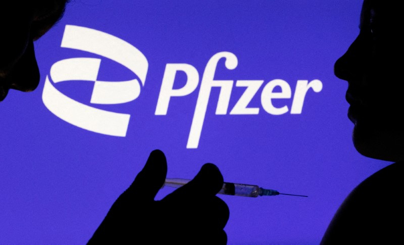 &copy; Reuters. FOTO DE ARCHIVO. Imagen de ilustración de personas con una jeringuilla con aguja delante del logo de Pfizer. 11 de diciembre de 2021. REUTERS/Dado Ruvic