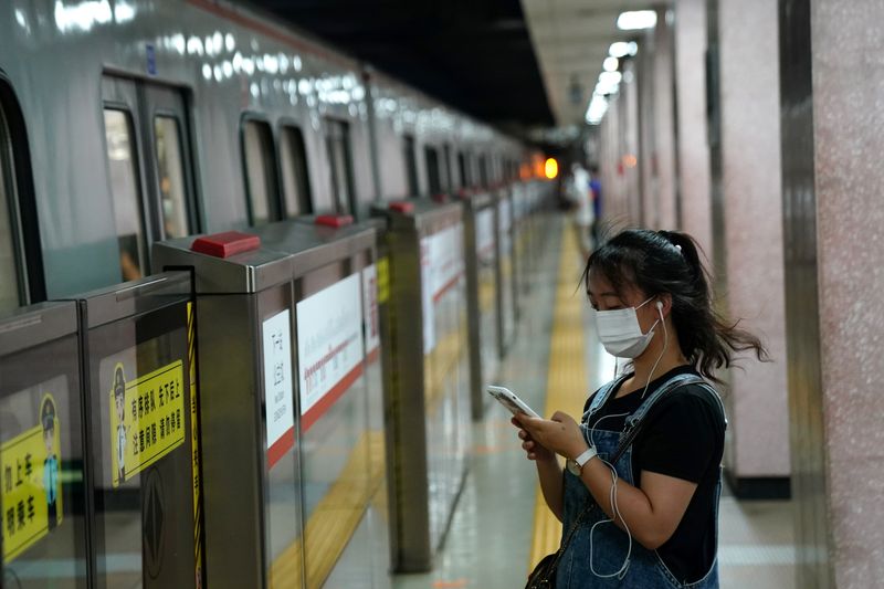 &copy; Reuters. FOTO DE ARCHIVO. Una mujer mira su teléfono inteligente mientras espera el metro en Pekín, China. 11 de agosto de 2020. REUTERS/Tingshu Wang