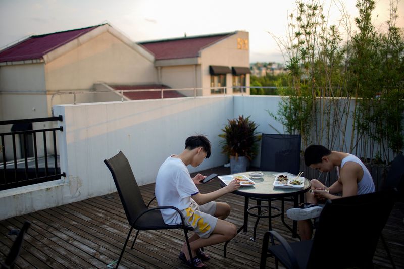 &copy; Reuters. Adolescentes verificam seus celulares enquanto jantam em um café em Xangai
REUTERS