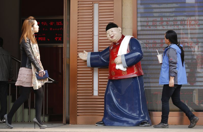 © Reuters. People walk past a statue, placed there to promote a restaurant, at a shopping district in Beijing April 3, 2013. REUTERS/Kim Kyung-Hoon/Files