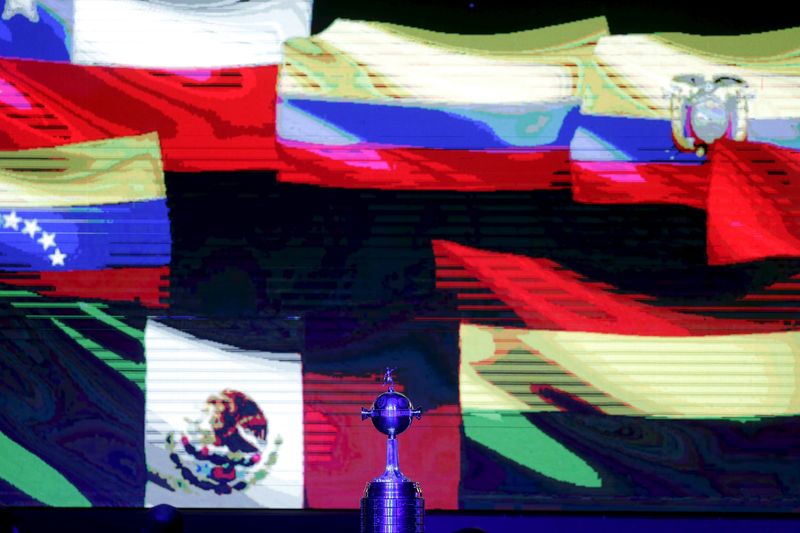 &copy; Reuters. FOTO DE ARCHIVO: El trofeo de la Copa Libertadores frente a las banderas de varios países americanos en una pantalla en la sede de la Confederacion Sudamericana de Futbol (CONMEBOL) en Luque, Paraguay, el 22 de diciembre de 2015. REUTERS/Jorge Adorno