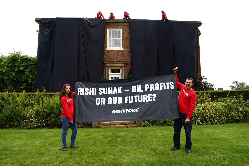 © Reuters. Greenpeace activists hold a banner while others cover British Prime Minister Rishi Sunak's £2m manor house in oil-black fabric in protest of his backing for a major expansion of North Sea oil and gas drilling amidst a summer of escalating climate impacts, in Yorkshire, Britain August 3, 2023. Greenpeace/Handout via REUTERS