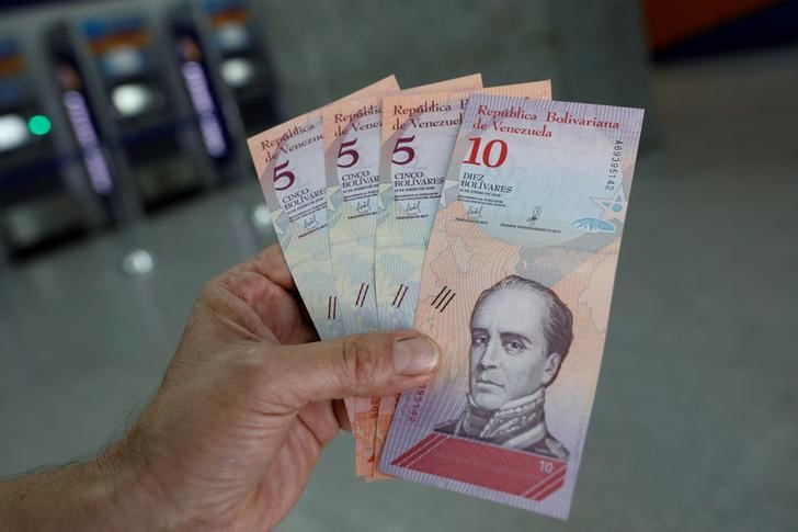 &copy; Reuters. Foto de archivo de un hombre sosteniendo billetes de 5 y 10 bolívares tras hacer un retiro de un cajero automático en Caracas 
Ago 20, 2018. REUTERS/Carlos Garcia Rawlins