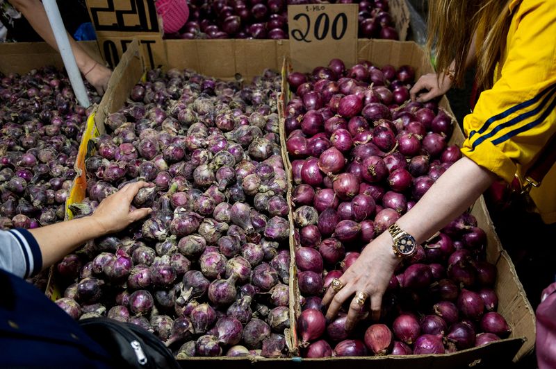 © Reuters. FILE PHOTO: People buy onions displayed at a stall in a public market in Manila, Philippines, January 28, 2023. REUTERS/Lisa Marie David/File Photo