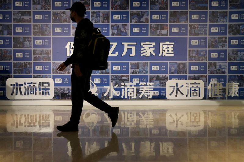 &copy; Reuters. FILE PHOTO: A man walks past a billboard with signs of Tencent-backed Chinese online insurance technology firm Waterdrop Inc ahead of the company’s U.S. initial public offering (IPO) on New York Stock Exchange (NYSE), in Beijing, China May 7, 2021. REUT