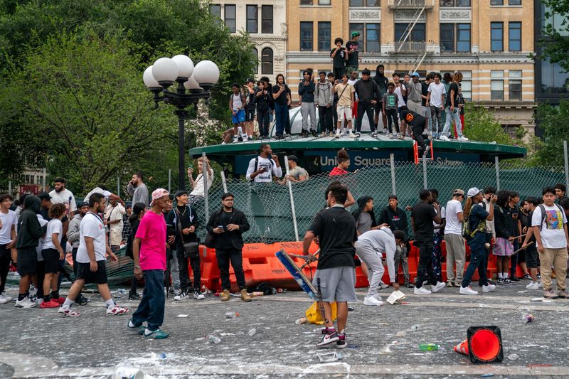 © Reuters. People stand on top of a subway station entrance to protect themselves after popular live streamer Kai Cenat announced a 