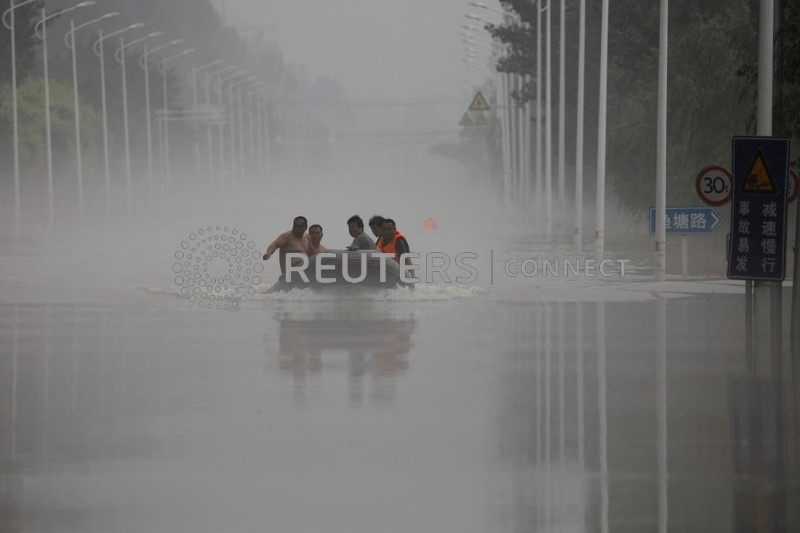 &copy; Reuters. أشخاص يركبون قاربا عبر طريق غمرته مياه الأمطار والفيضانات التي جلبتها بقايا إعصار دوكسوري في تشوتشو بمقاطعة هيبيه الصينية يوم 3 أغسطس آب 2023.