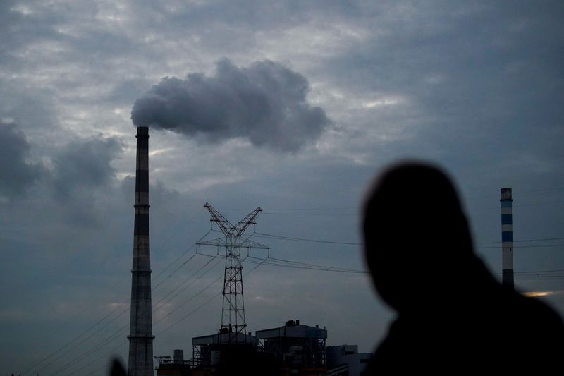 © Reuters. FILE PHOTO: A man walks past a coal-fired power plant in Shanghai, China, October 14, 2021. REUTERS/Aly Song/File Photo