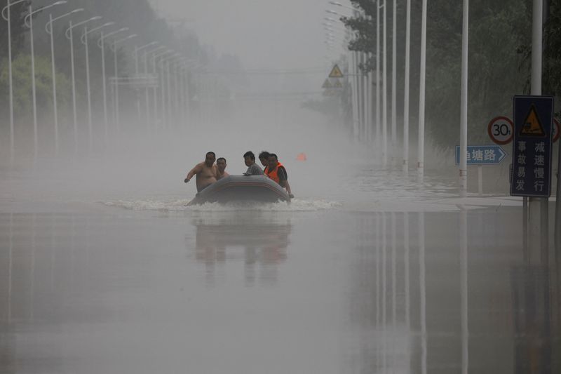 &copy; Reuters. Des gens traversent en bateau une route inondée après les pluies du typhon Doksuri, à Zhuozhou, dans la province du Hebei, en Chine. /Photo prise le 3 août 2023/REUTERS/Tingshu Wang