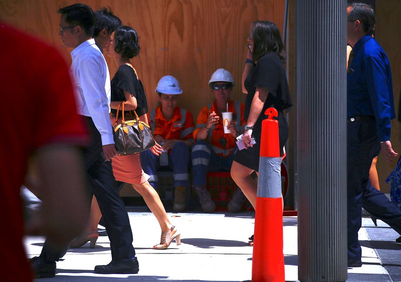 &copy; Reuters. Pedestrians walk past workers sitting near a construction site eating their lunch in the central business district (CBD) of Sydney in Australia, February 13, 2018.   REUTERS/David Gray