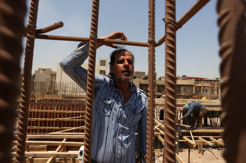 &copy; Reuters. عامل ينعش نفسه أثناء عمله في موقع بناء لمبنى مدرسة جديدة خلال حرارة الصيف الحارقة في بغداد بالعراق يوم 17 يوليو تموز 2023. تصوير: أحمد سعد - رويت
