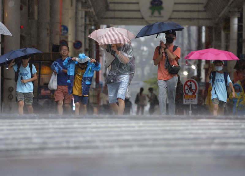 &copy; Reuters. Passersby walk in a heavy rain and wind caused by Typhoon Khanun in Kagoshima on Japan's third-largest island Kyushu, August 8, 2023, in this photo taken by Kyodo. Mandatory credit Kyodo via REUTERS
