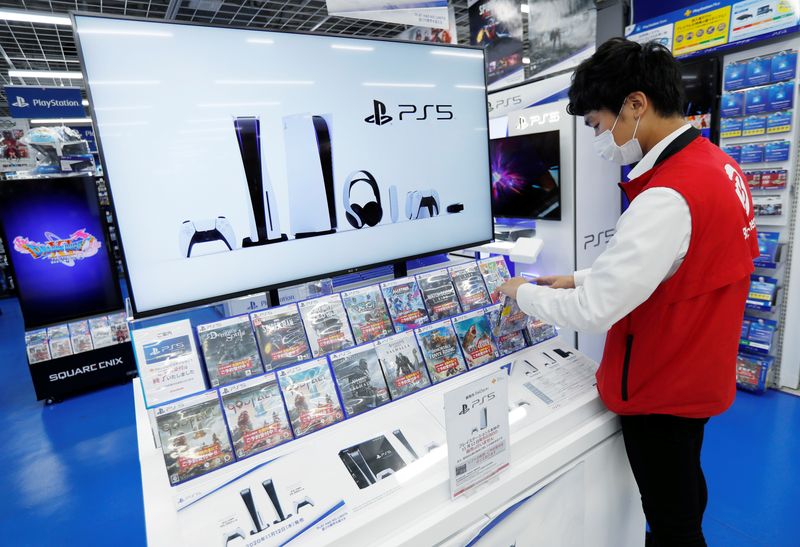 © Reuters. FILE PHOTO: An employee of the consumer electronics retailer chain Bic Camera works at the promotion display of the Sony PlayStation 5 game console and its gaming software, ahead of the game console's official launch, in Tokyo, Japan November 10, 2020.  REUTERS/Issei Kato/File Photo