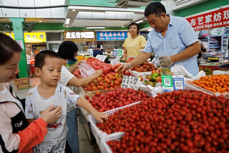 © Reuters. Clientes seleccionan tomates en un puesto de un mercado matutino de Pekín, China. 9 de agosto de 2023. REUTERS/Tingshu Wang
